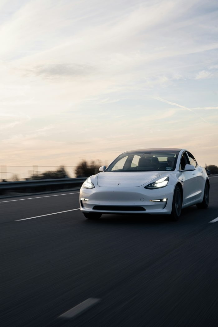 A white Tesla driving on a highway road