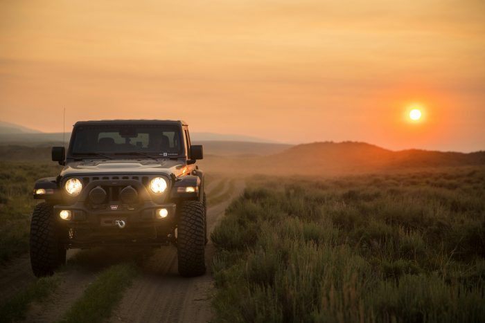 Jeep driving through a desert terrain at sunset