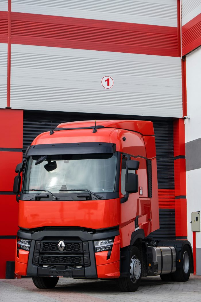 A red heavy truck parked in front of a warehouse