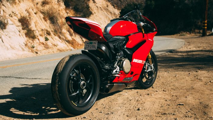 A red Ducati parked alongside a highway road in an arid landscape with natural rock formations